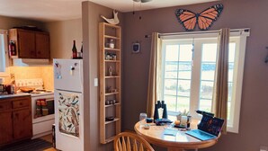 Una cocina con armarios de madera, un refrigerador, un microondas y una mesa de comedor con una silla.