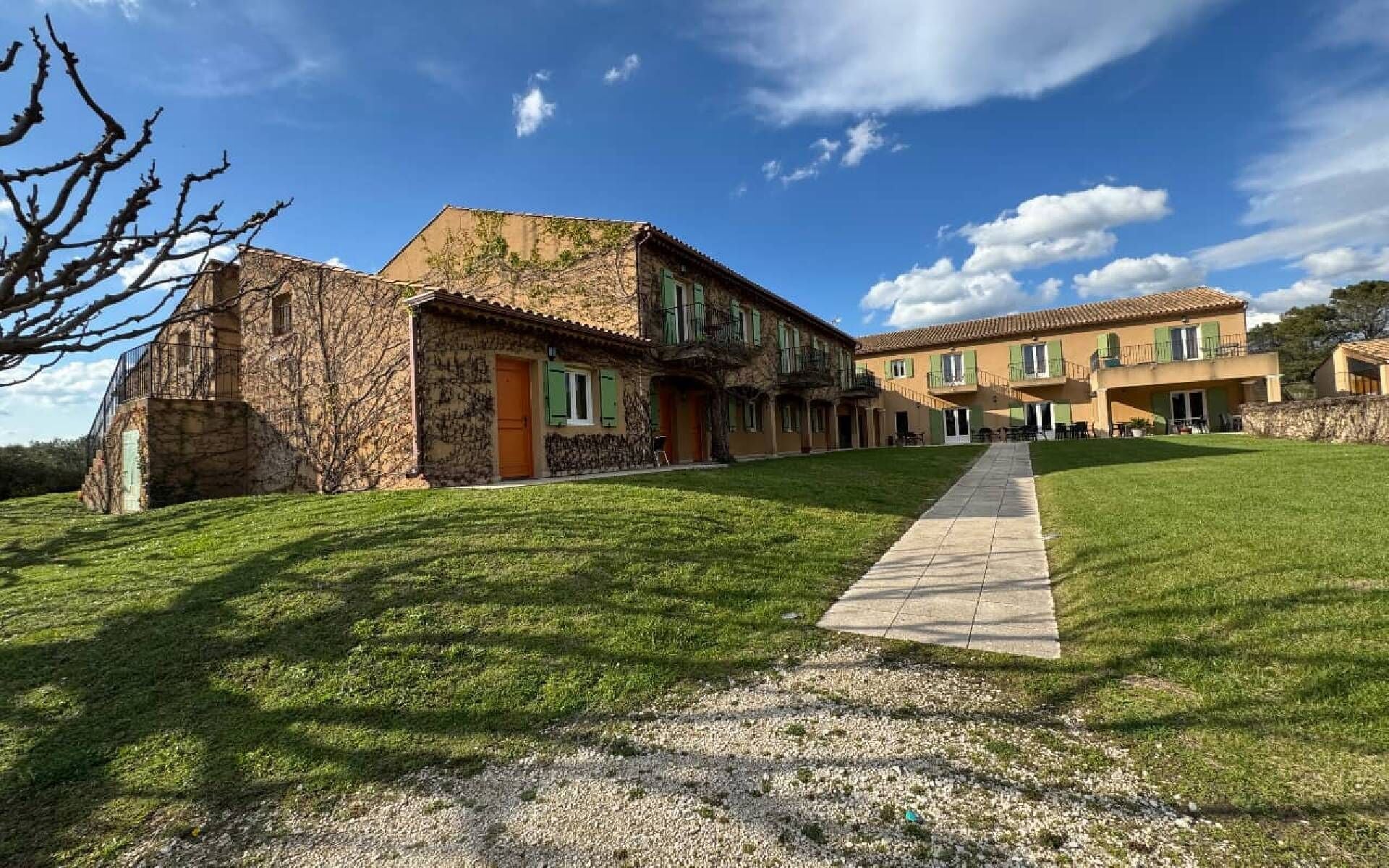A building with a stone facade, a paved walkway, and a grassy lawn.