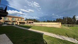 A building with a patio area, a stone wall, and a grassy lawn. - Traveling in the 21st century is all about comfort (Mouriès)