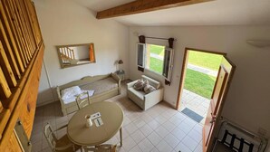 A room with a bed, a sofa, a table, and a window with a view of a lawn. - Traveling in the 21st century is all about comfort (Mouriès)