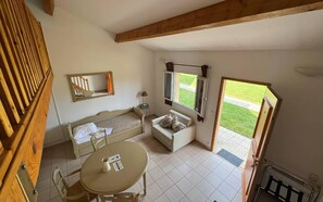 Ein Zimmer mit einem Bett, einem Sofa, einem Tisch und einem Fenster mit Blick auf eine Rasenfläche.