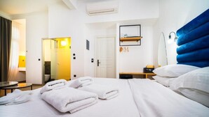 Habitación de hotel con cama, mesita de noche, lámpara y baño visible a través de una puerta abierta.