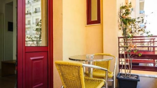 Un piso a cuadros, una puerta roja y una pequeña mesa con sillas.