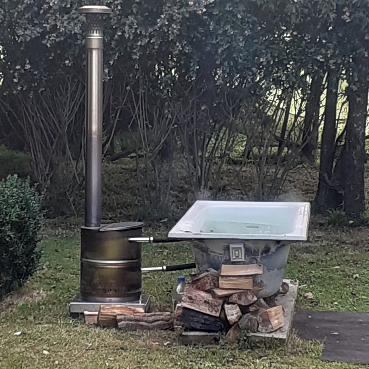 An outdoor cooking setup with a wood stove and a metal chimney.