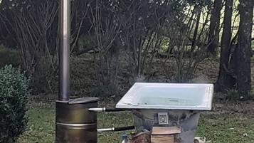 An outdoor cooking setup with a wood stove and a metal chimney.