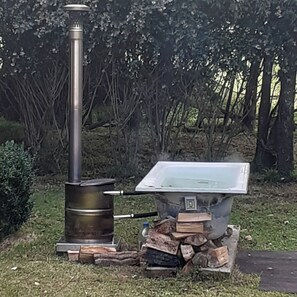 An outdoor cooking setup with a wood stove and a metal chimney. - Country Charm Cozy  Cottage - Meets NZ HH heating Cert. Outdoor Wood fired bath (Bunnythorpe)