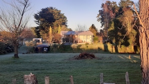 A rural property with a house, a fenced yard, and a large tree. - Country Charm Cozy  Includes  Out door wood fired Iron  Hot tub+ Breakfast (Bunnythorpe)