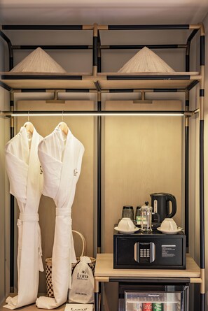 A hotel room with a wardrobe, a hair dryer, a coffee maker, and a minibar.