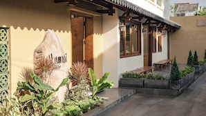 A building with a large stone sign, wooden doors, and a covered outdoor seating area with planters. - Lumi Hoi An Hotel (Da Nang)