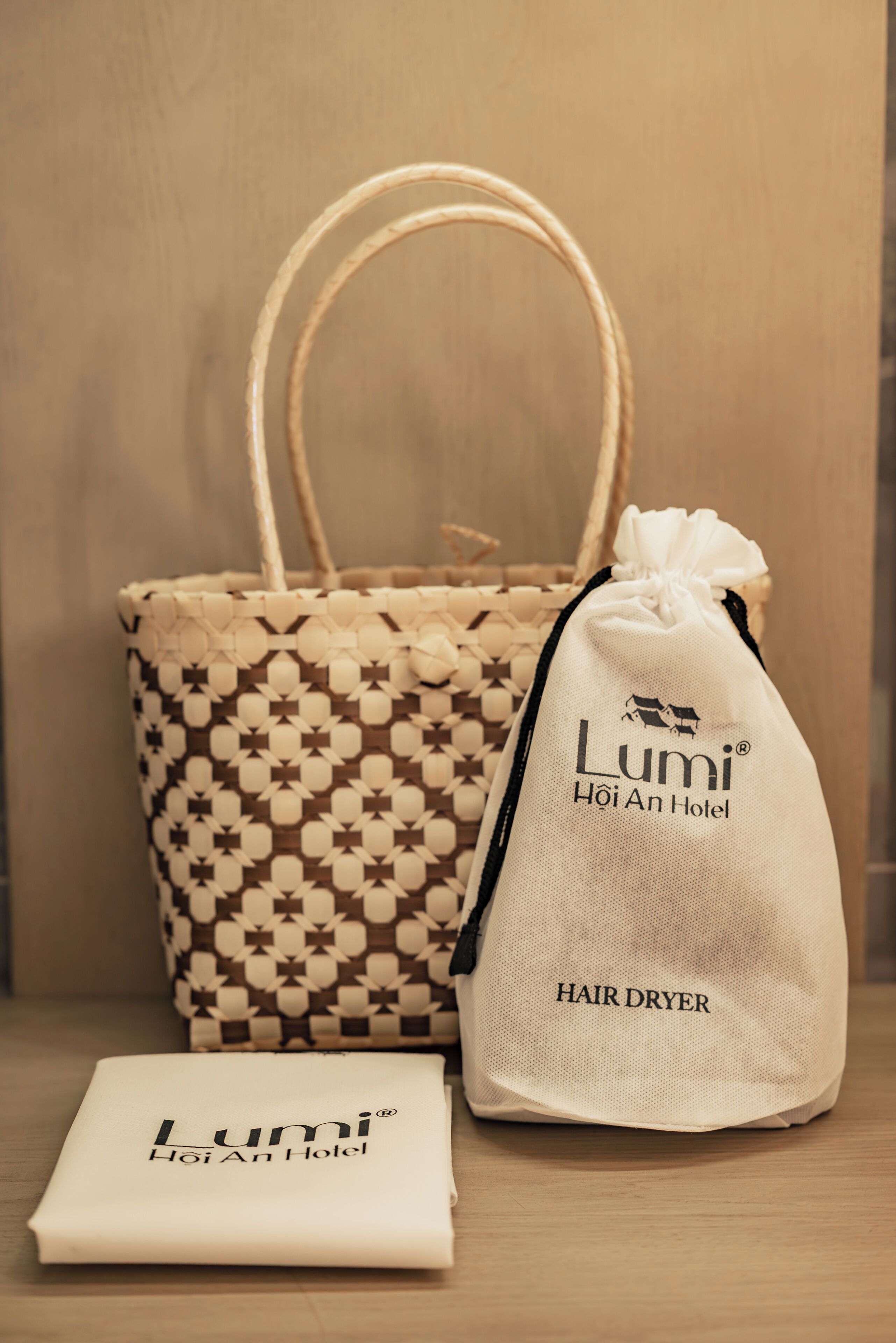 Un sèche-cheveux de la marque LUMI Hoi An Hotel, un sac fourre-tout à motifs et un tissu blanc.