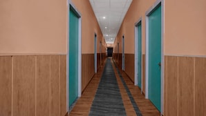 A long hallway with doors on both sides, leading to individual rooms. - Deluxe Jalukbari Bus Stand Velvet Stay (Guwahati)