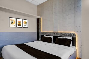 A neatly made bed with a dark headboard, a wall with a star pattern, and three framed artworks above the bed. - Deluxe Jalukbari Bus Stand Velvet Stay (Guwahati)