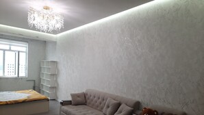A modern living room with a sofa, a teddy bear, and a chandelier.
