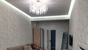 A bedroom with a bed, a sofa, a teddy bear, a wardrobe, a mirror, and a chandelier.