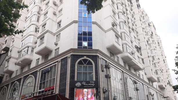 A multi-story building with a prominent entrance, large windows, and a signboard.
