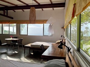 A room with a wooden table, chairs, a bed, a desk, and a window with a view. - Private ocean view room on Minca Sintropia sustainable lodge & coffee finca (Minca)