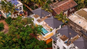 A residential area with multiple houses, a swimming pool, and lush greenery. - ELIVAAS Purple Coral Luxe 5-BHK Villa (Assagao)