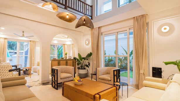 A spacious living room with a large window, a ceiling fan, and a unique coffee table. - ELIVAAS Purple Coral Luxe 5-BHK Villa (Assagao)