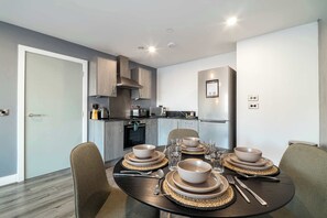 Una cocina moderna con electrodomésticos integrados, una mesa de comedor para cuatro personas y una zona de estar independiente.