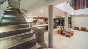 A spacious interior with a staircase, a central column, and a seating area with a sofa and coffee table. - Luxury 9BR Bingin Villa - Large Pool, Near Beach (Kecamatan Kuta Selatan)