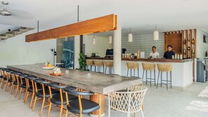 A modern kitchen with a bar area, wooden ceiling, and bar stools. - Luxury 9BR Bingin Villa - Large Pool, Near Beach (Kecamatan Kuta Selatan)