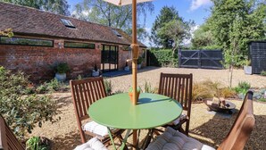 En terrasse med bord og stole, en murstensbygning og et afspærret område.