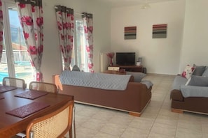 Ein Wohnzimmer mit einer Couch, einem Fernseher und einem Essbereich mit Stühlen und einem Tisch.