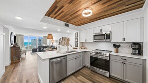 Een moderne keuken met witte kasten, roestvrijstalen apparatuur en een houten plafond.