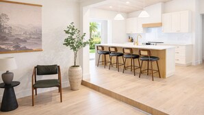 Una cucina moderna con isola centrale, sgabelli da bar e una pianta in vaso.