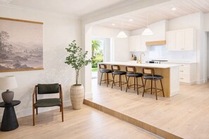 Eine moderne Küche mit einer zentralen Kochinsel, Barhocker und einem Blumentopf.