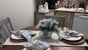 A dining table set for four with a decorative plant centerpiece, a coffee machine, and a sink in the background. - Cozy on the coast of Tybee (Tybee Island)