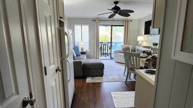 A hallway with a ceiling fan, a dining area with a table and chairs, and a view of a balcony. - Cozy on the coast of Tybee (Tybee Island)
