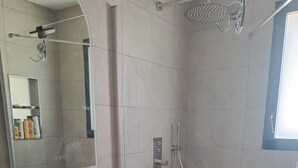 A bathroom with a large mirror, a vessel sink, a shower, and a toilet.
