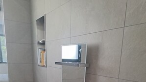 A bathroom with a large mirror, a shelf with toiletries, and a wicker basket on the floor.