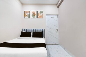 A bedroom with a bed, a door, and three framed artworks on the wall.