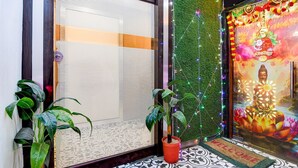 A room with a closed sliding door, a green wall with a decorative string of lights, a Buddha mural, and two potted plants. - Deluxe With Twin Bed BK International (Kolkata)