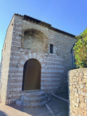 A stone building with a central arched doorway, a small window, and a tiled roof. - La Casita of Marco and Nicoletta (Assisi)