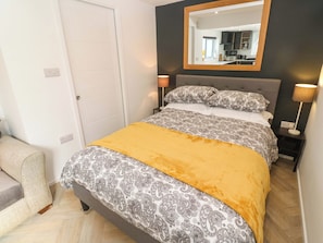 A bedroom with a bed, bedside lamps, a mirror, and a door.