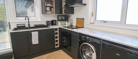 Una cocina moderna con lavavajillas incorporado, microondas y pileta.