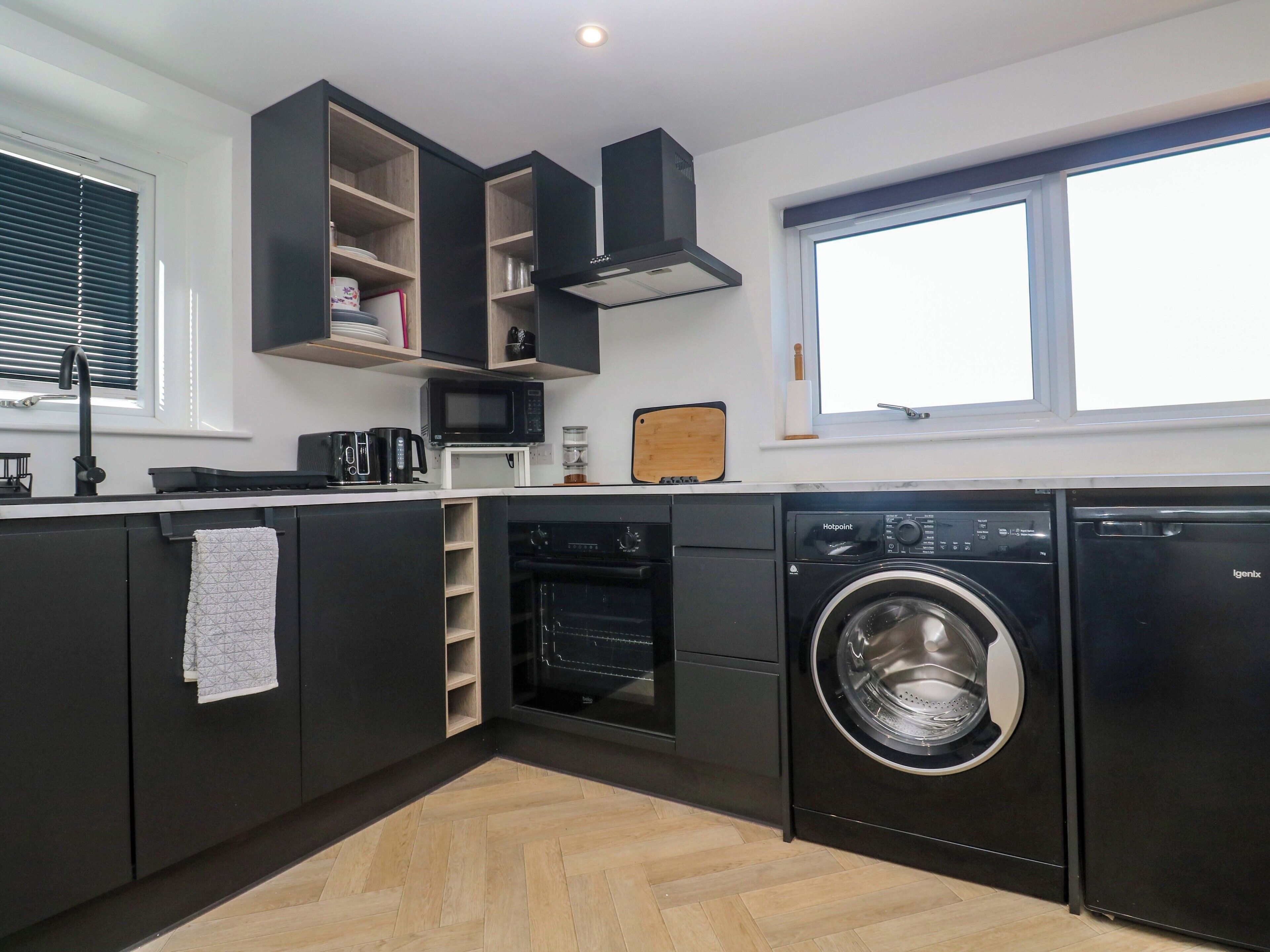 A compact kitchen with built-in appliances, a microwave, a coffee maker, and a washing machine.