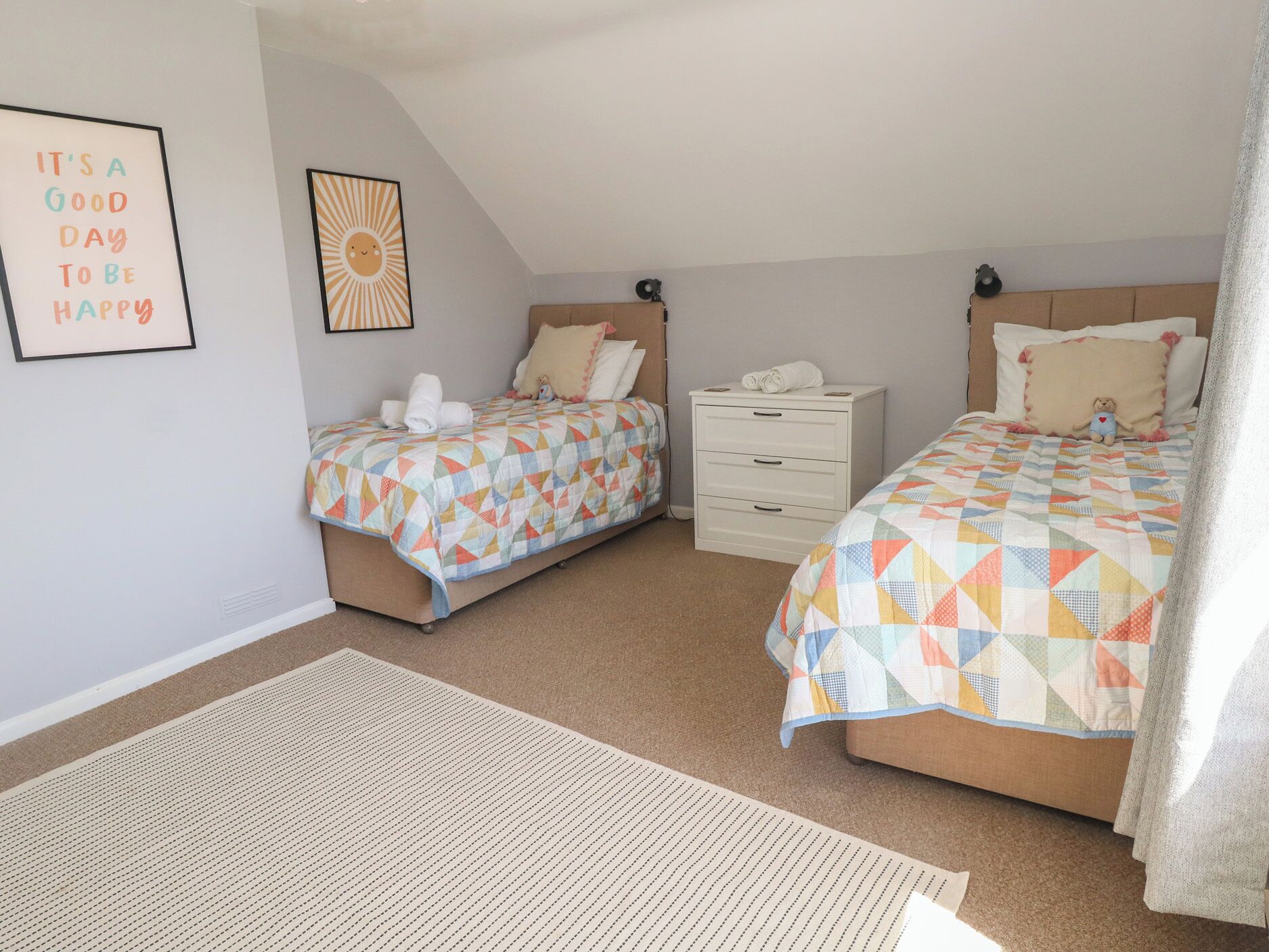 A bedroom with two beds, a nightstand, a wall clock, and a framed quote.