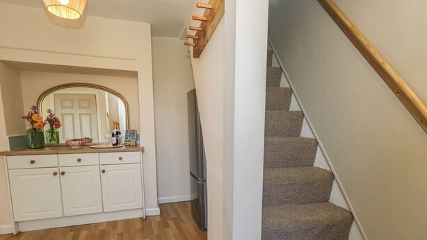 A staircase leading to a landing with a wooden handrail and carpeted steps. - Mallow Cottage (Swanage)