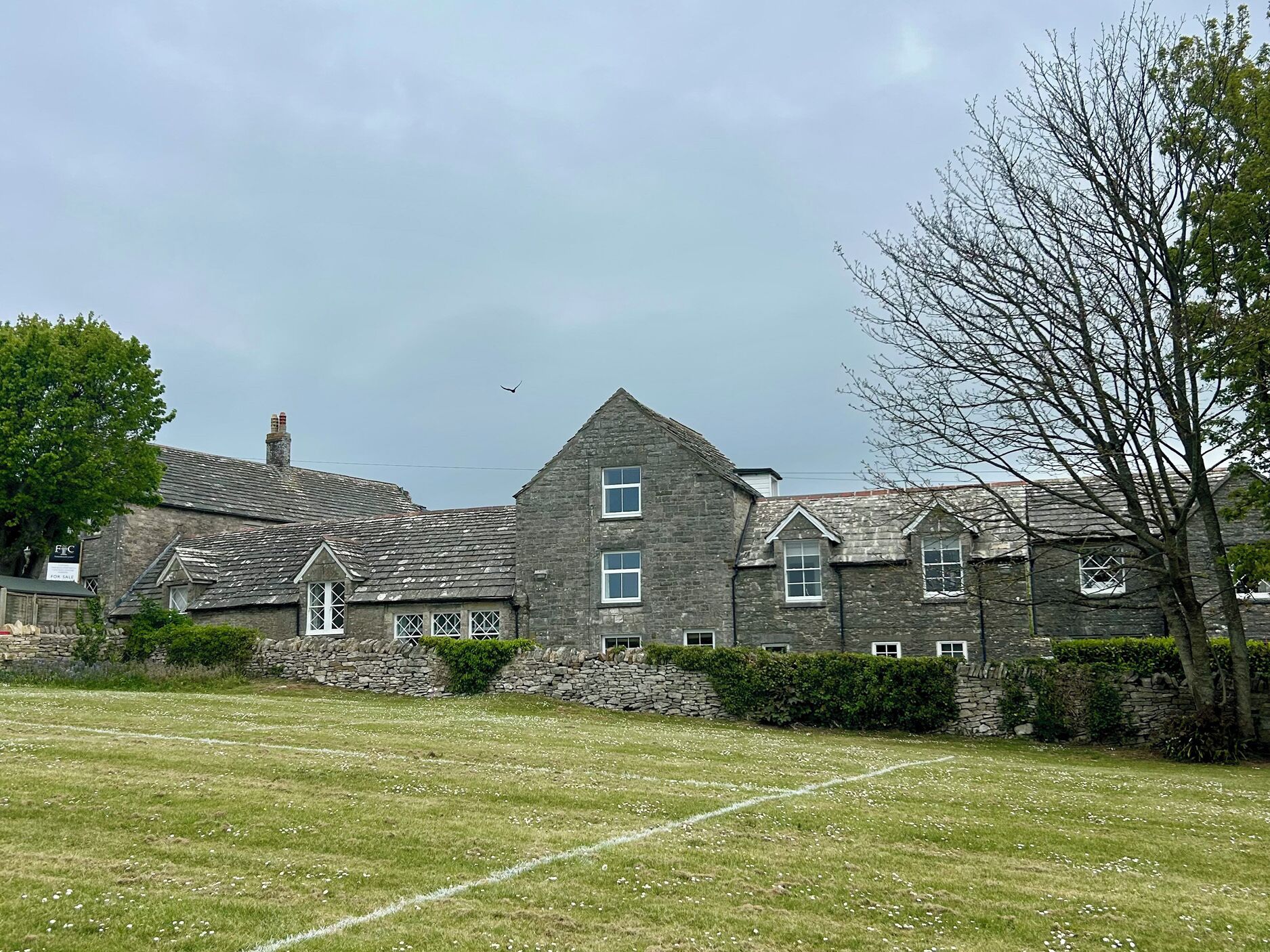 A large stone building with multiple windows and a grassy lawn in front.