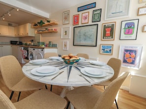 A dining area with a round table, chairs, and a bowl of bread. - Mallow Cottage (Swanage)