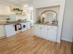 A modern kitchen with a washing machine, a stove, and a sink. - Mallow Cottage (Swanage)