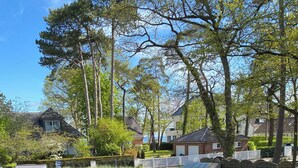 Una calle residencial con casas, coches aparcados y una valla blanca.