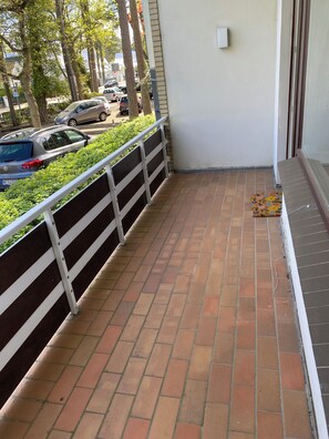 A balcony with a tiled floor, a metal railing, and a small floral mat. - Strandallee 170, Baltic Sea side in 2nd row to the beach (Timmendorfer Strand)