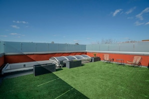 A rooftop terrace with artificial grass, outdoor seating, and a clear sky. - Stylish 3BR Wimbledon Roof Terrace & Parking (London)