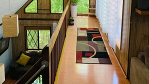 Un intérieur en bois avec un plafond en pente, un escalier et une vue sur la verdure à l’extérieur.