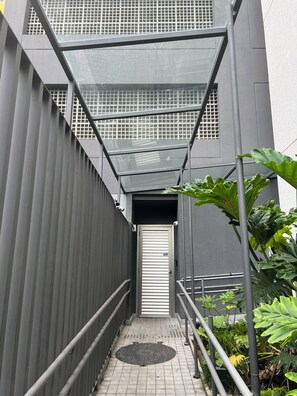 Eine schmale, geschlossene Treppe mit Metallgeländern, einer Glasüberdachung darüber und einer Tür am Ende.
